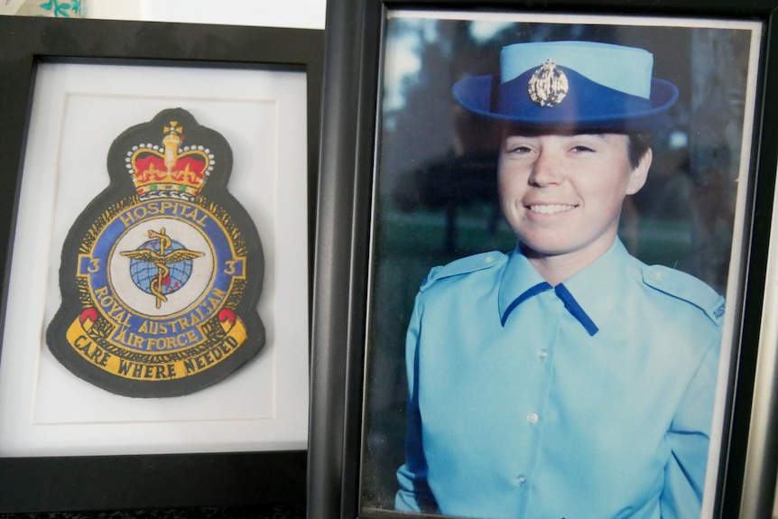 A photograph of a lady in her Royal Australian Air Force uniform in a frame and a RAAF badge in another frame.