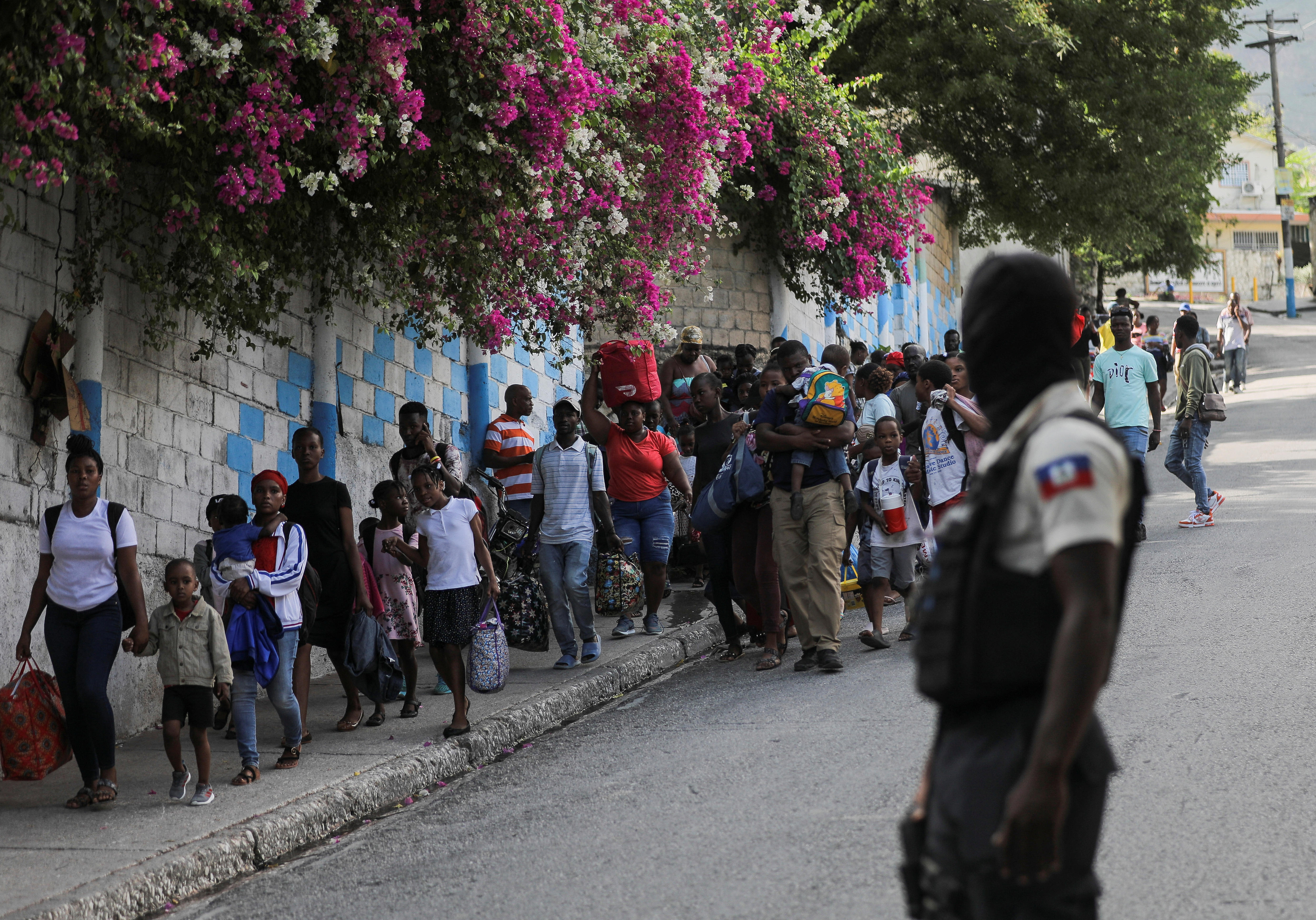 A police officer looks on as a large group of people make their way along a street