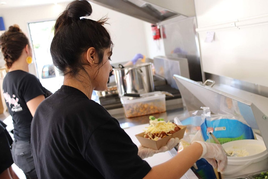 Malaika and another teen makes food for customers in the Good Grub Club food van.