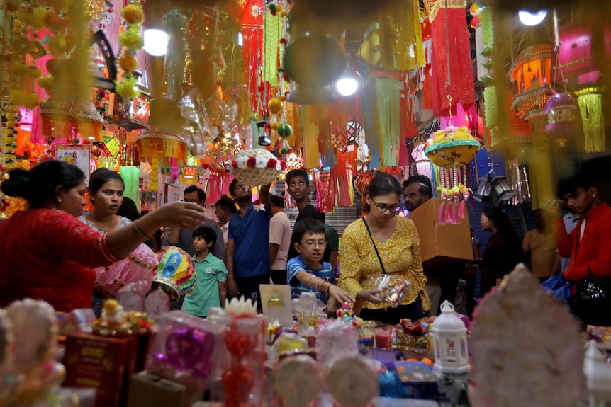 People crowd around a table filled with lanterns and candles. 