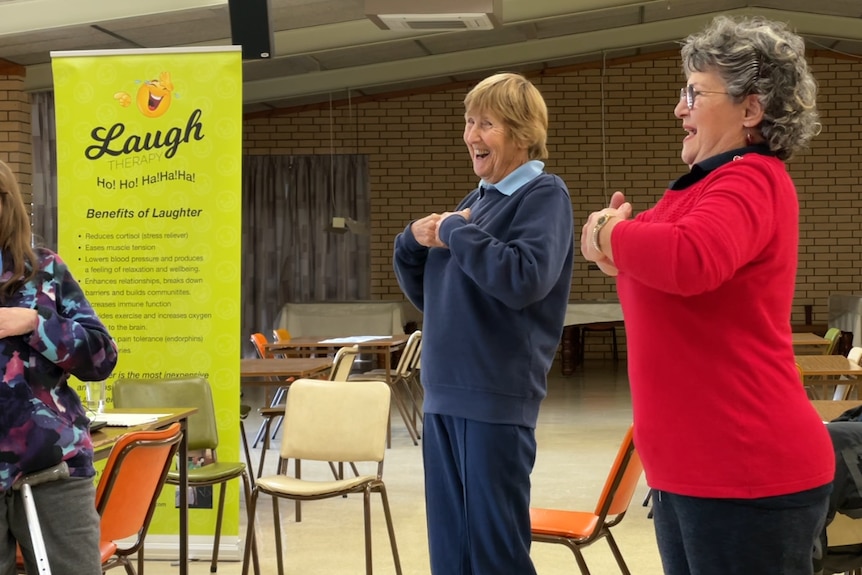 Two women standing and laughing with their arms folded by their chest