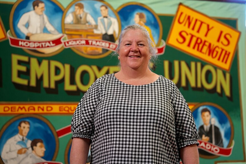 A woman stand in front of banner saying "employees' union".