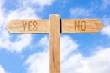 A sign post with pathways saying Yes and No against a blue sky