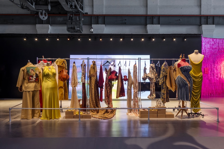 A collection of Nicol & Ford designs on display at the Powerhouse Museum in front of a large projection screen.
