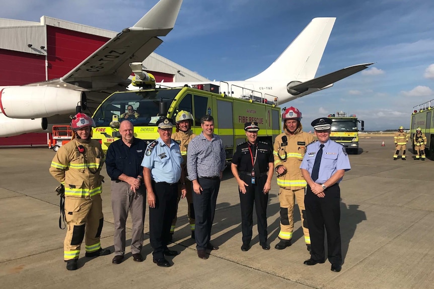 A group shot of senior police and emergency services personnel on the tarmac after a emergency landing.