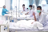 Three of the 12 boys are seen recovering in their hospital beds.