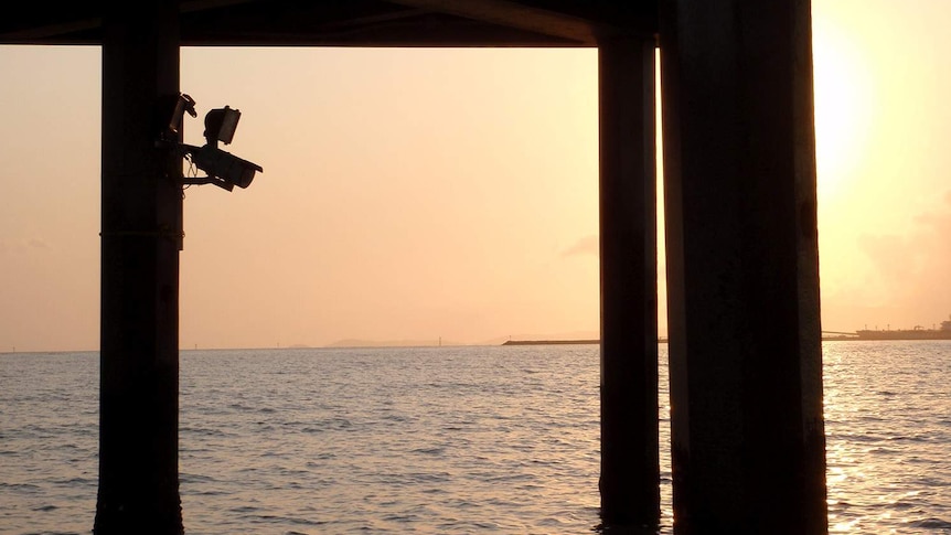 A camera on a wharf silhouetted in the dying light of sunset