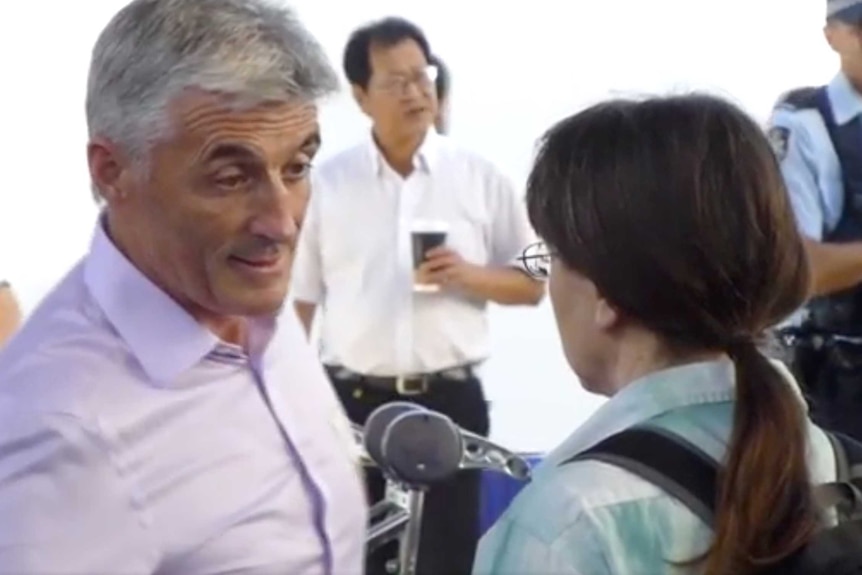 A man in a purple shirt speaking to a woman with long dark hair