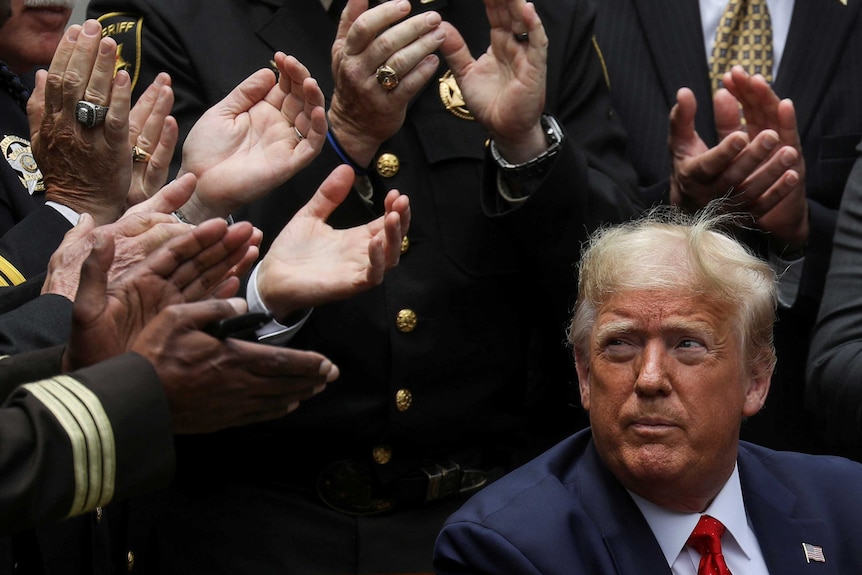 Donald Trump surrounded by men clapping for him