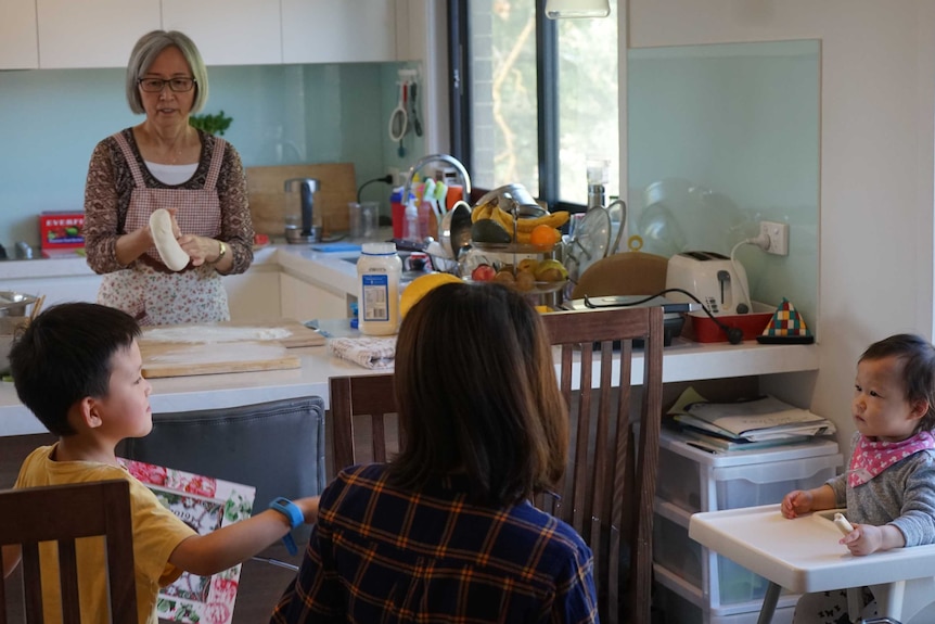 Lee Xia at the kitchen bench, wearing an apron and making dough for her son's family.