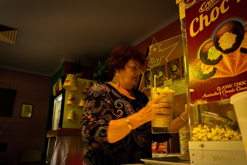 A woman using a popcorn machine.