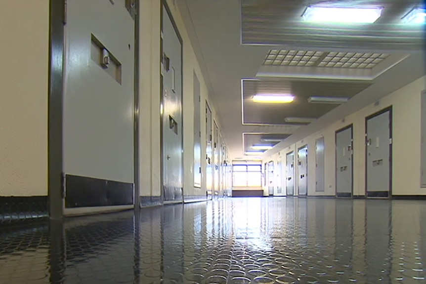 A prison hallway lined with doors to jail cells.