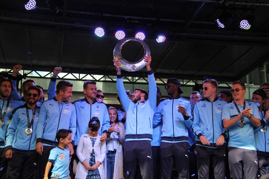 Sydney FC players celebrate with the A-League trophy on stage at Pitt Street mall on May 8, 2017.