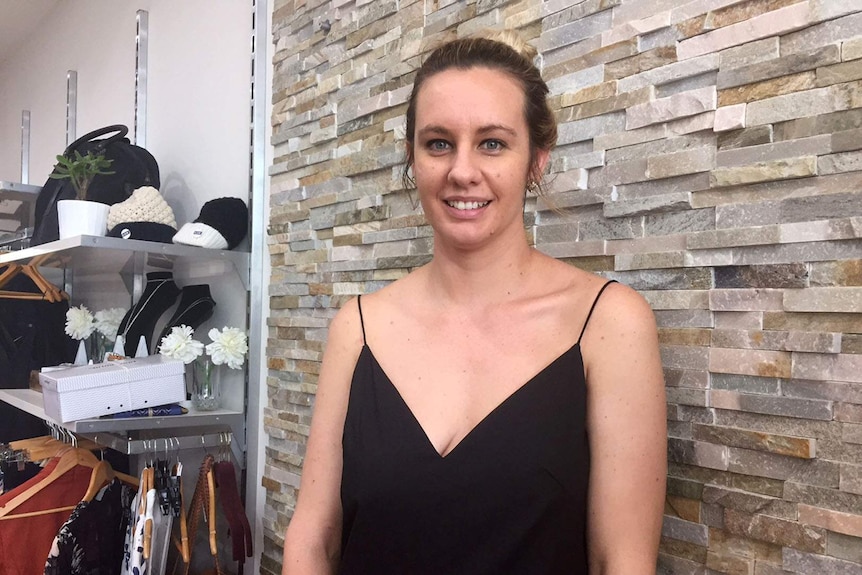 A young woman stands inside a clothing and accessories shop