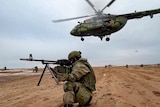 A Russian marine takes position in front of a helicopter during a training exercise