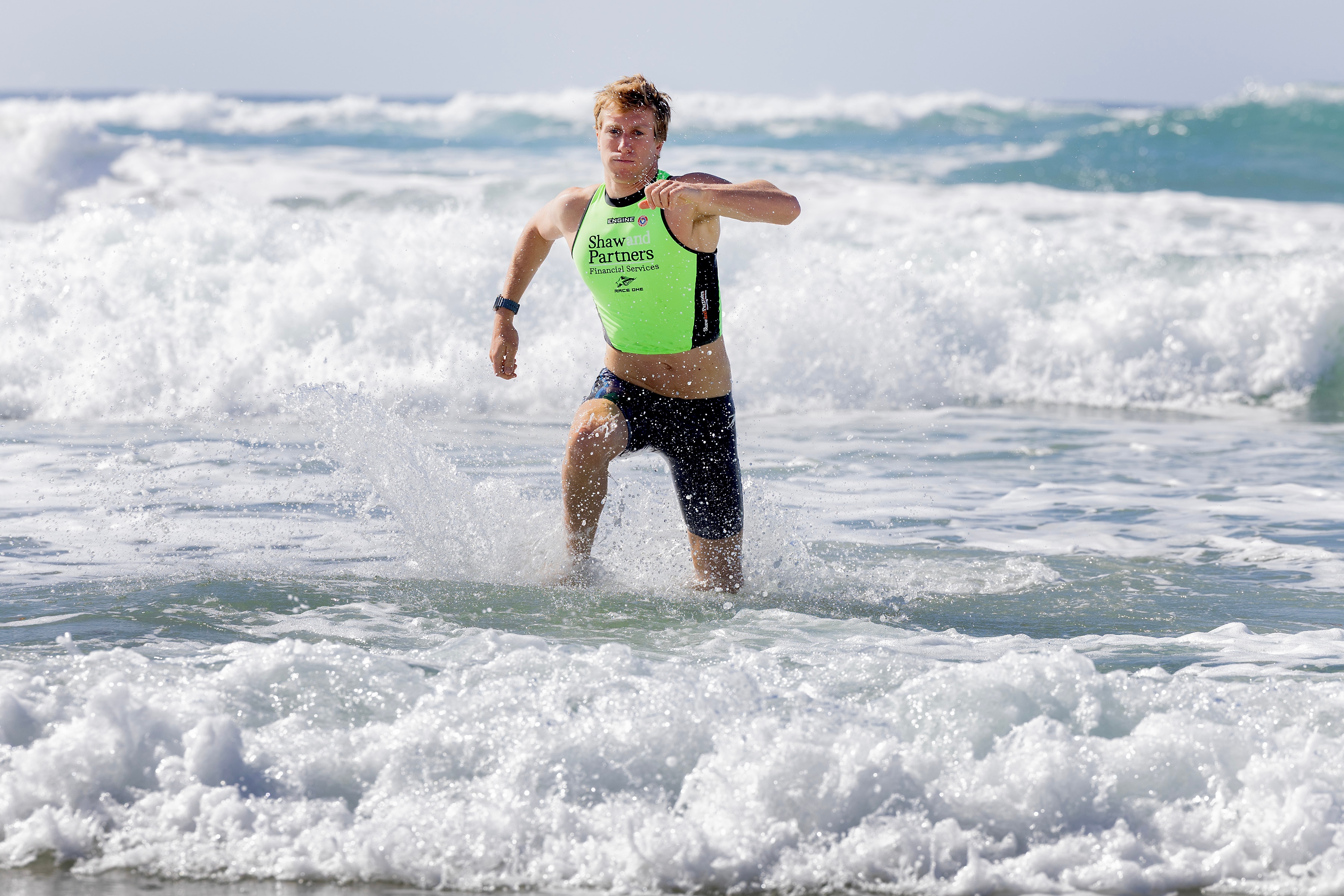 Charlie Verco runs out of the surf, wears green vest.