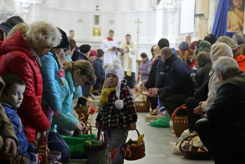 Catholic believers wait for their traditional Easter cakes and painted eggs to be blessed in Minsk.