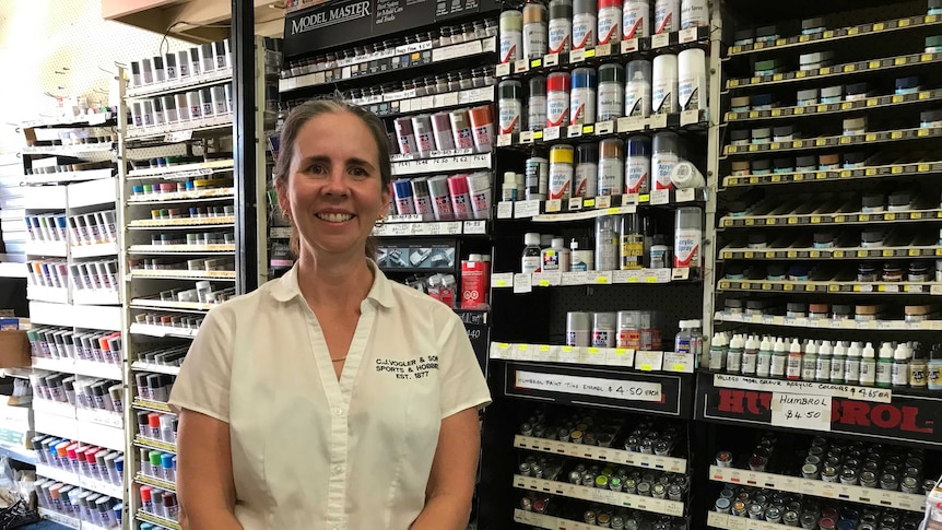 Leigh-anne Townsley stands behind the counter of the hobby shop. Paints and models stacked in the background