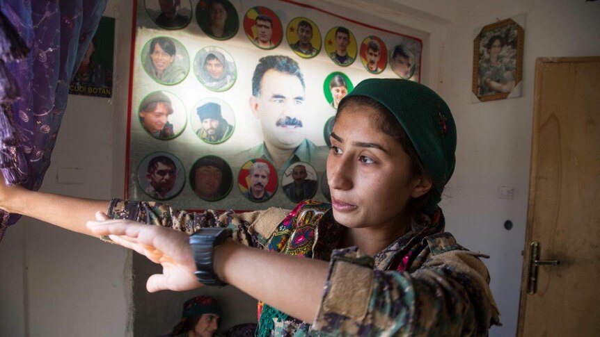 A YPJ member stands near a big banner with a picture for Kurdish jailed leader Abdullah Öcalan