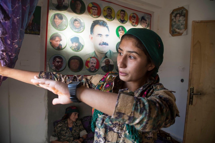 A YPJ member stands near a big banner with a picture for Kurdish jailed leader Abdullah Öcalan