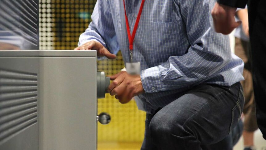 Man kneeling on floor with his hand on a security safe.