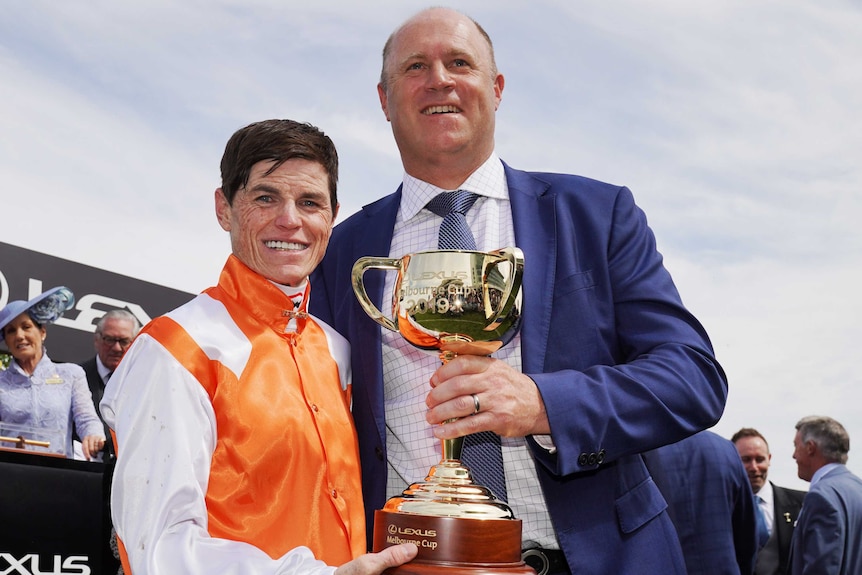 The winning jockey and trainer hold the Melbourne Cup at Flemington Racecourse after Vow and Declare's victory.