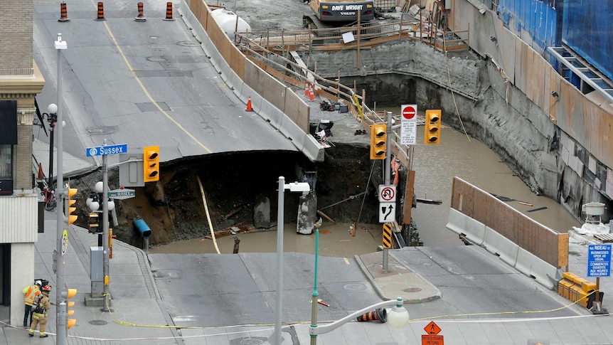 Workers look at a large sinkhole in Ottawa