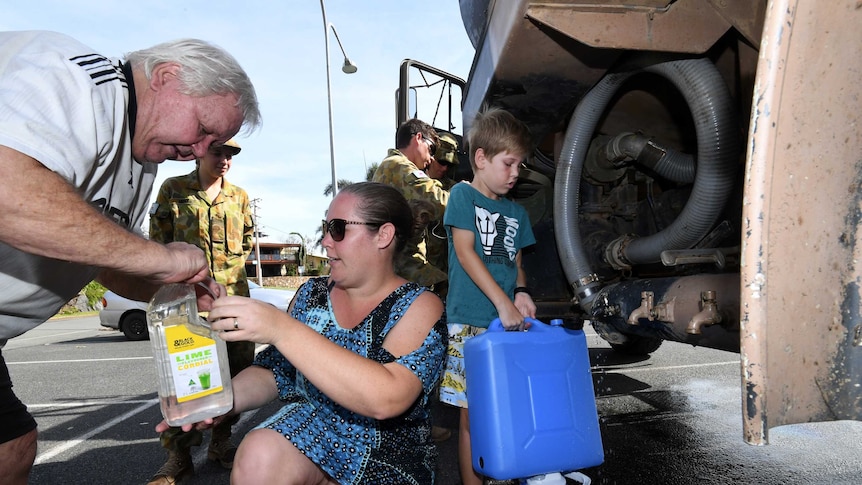 10-year-old Chad Allan and his mother Chloe collect water from an army tanker in Airlie Beach.