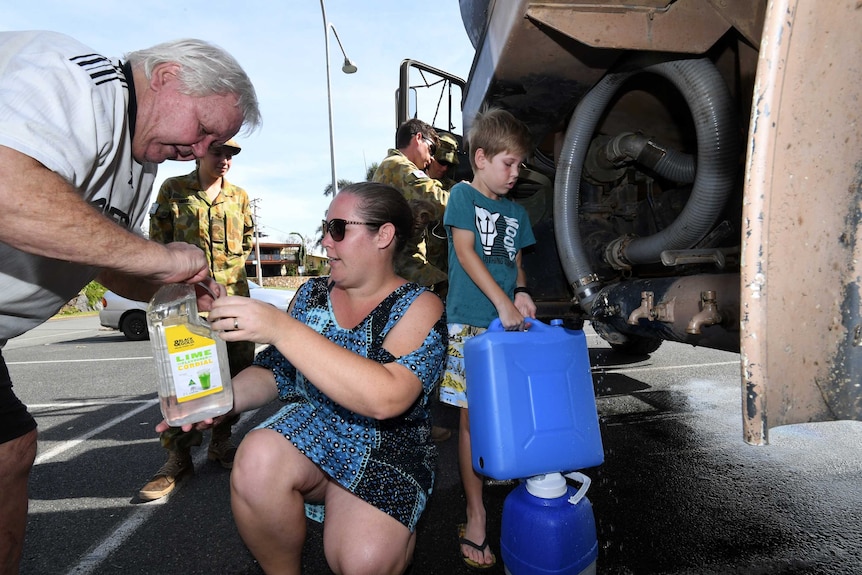 10-year-old Chad Allan and his mother Chloe collect water from an army tanker in Airlie Beach.
