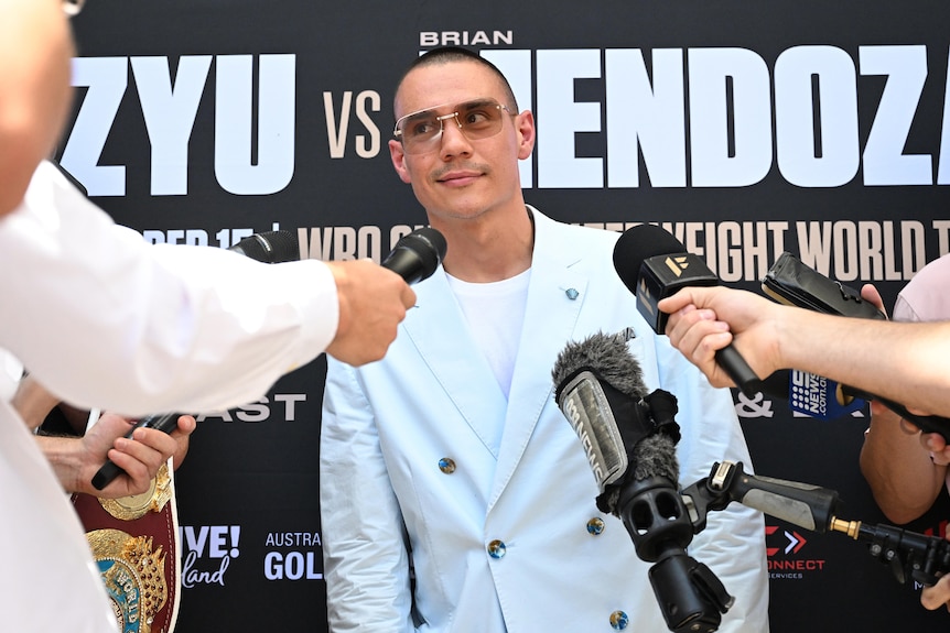 Boxer Tim Tszyu looks towards a reporter holding a microphone at a press conference.