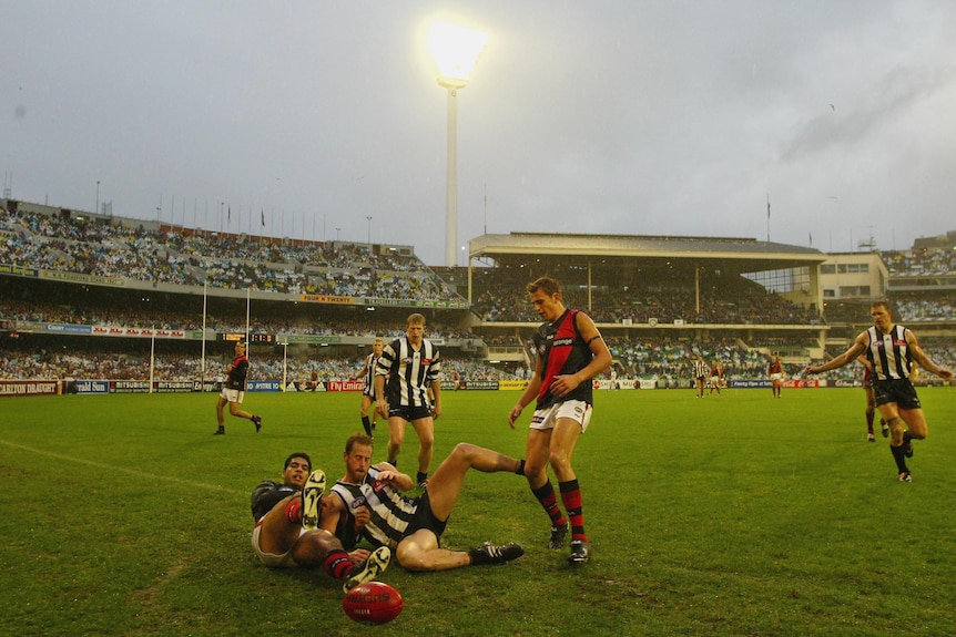 An AFL player slides towards the boundary during a match