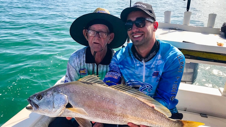 Ray Johnstone fishing with Mati Batsinilas in Moreton Bay holding their first big catch.