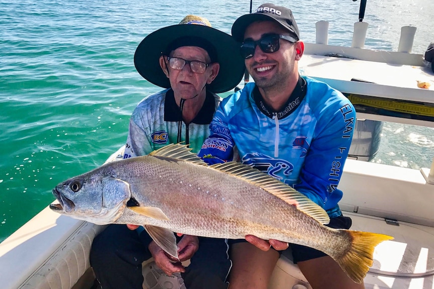 Ray Johnstone fishing with Mati Batsinilas in Moreton Bay holding their first big catch.