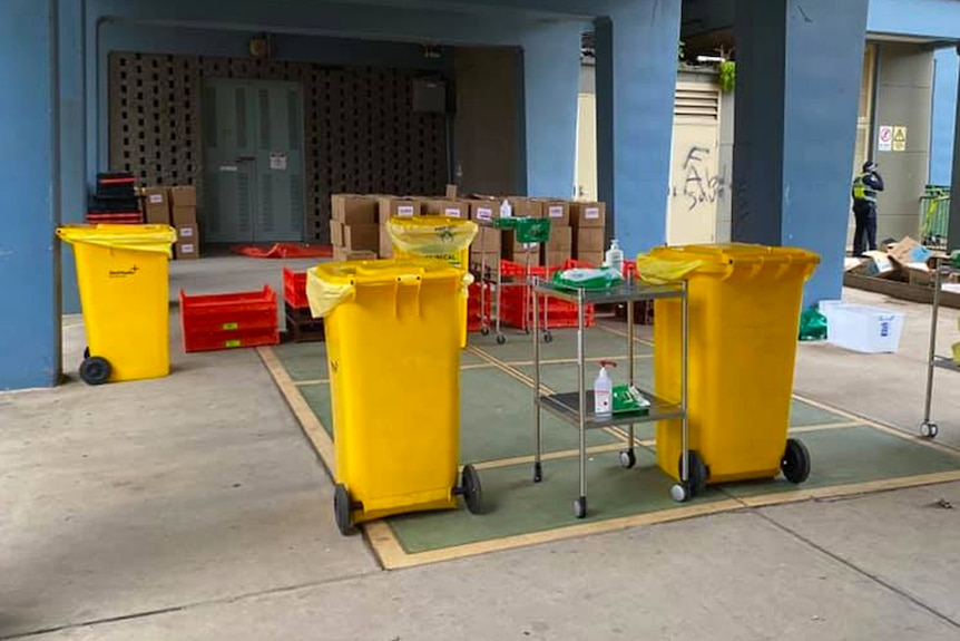 Yellow wheelie bins and cleaning equipment outside a public housing building