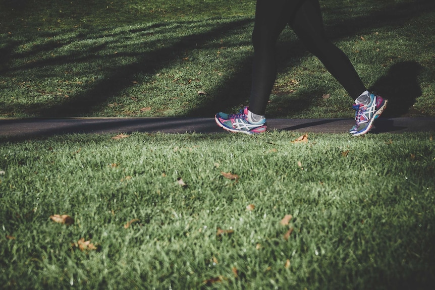 A woman runs along a park path, for a story about online exercise programs.