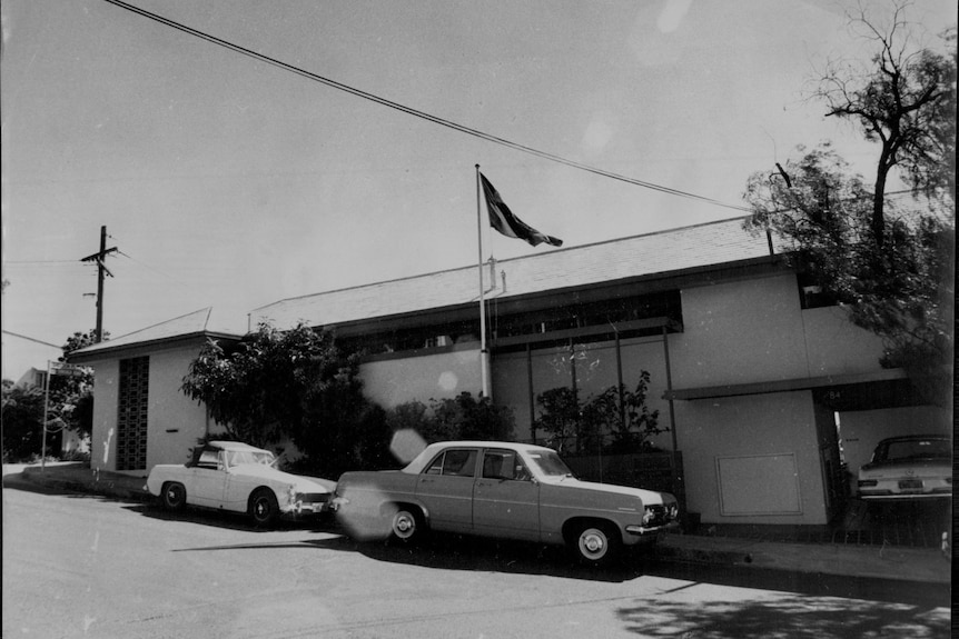 A flag flying on a house on a suburban street in black and white photo