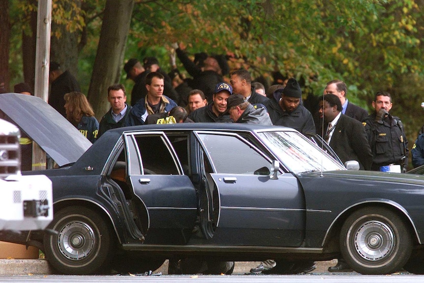 Police surround a car with the doors and boot open