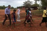 Terry Redman walking with Aboriginal children in a remote community.