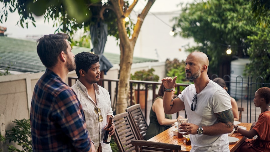 Shot of a group of young men having drinks at a dinner party outdoors.