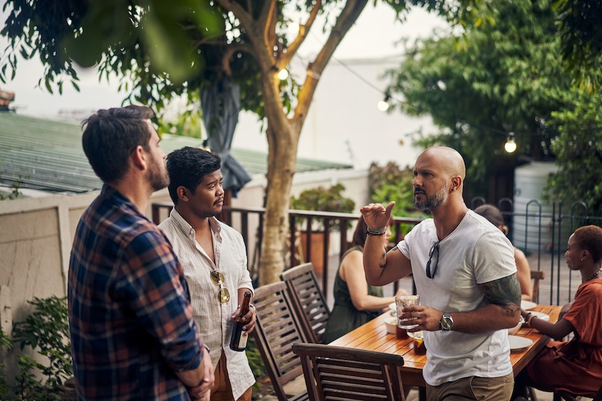 Shot of a group of young men having drinks at a dinner party outdoors.