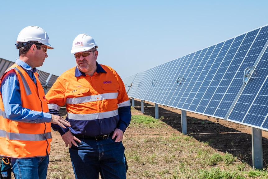 Deux hommes en uniforme haute visibilité dans une ferme solaire.