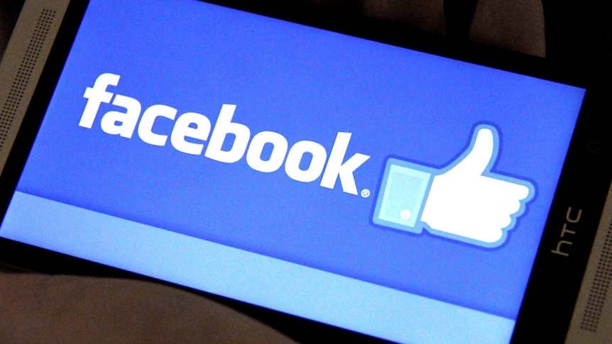 The Facebook logo is displayed on a smartphone screen in April 2014.