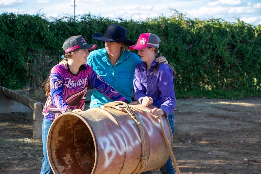 Mum Meg and her two daughters Tyler and Jacy around old metal drum used as for bull riding practice, November 2022.