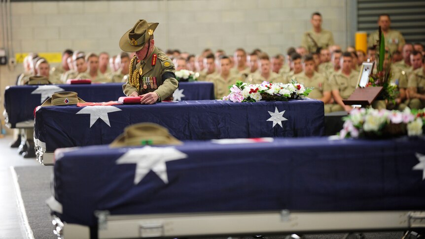Chief of Army Lieutenant General David Morrison, AO places the medals on Captain Bryce Duffy's casket