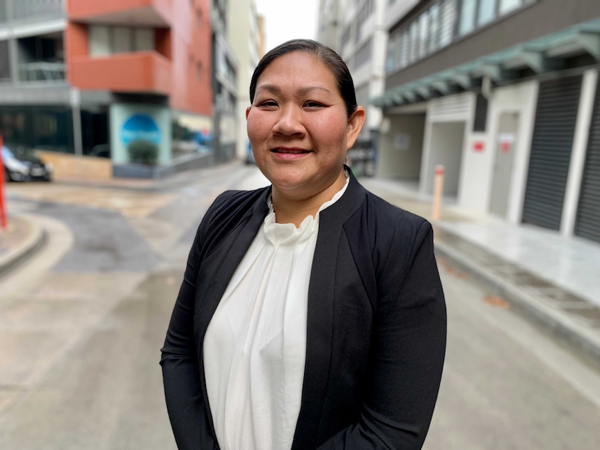 Emma Allen, director of Active Property Investing, stands in a street with apartments behind.