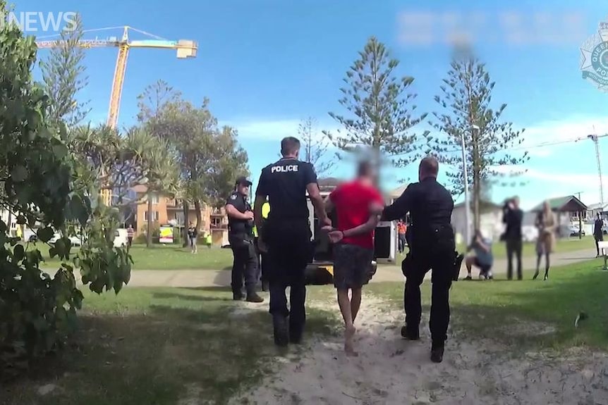 Police officers escort handcuffed man they arrested after he fled the airport on Queensland's Gold Coast.