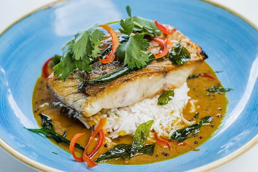 a cooked barramundi fillet on rice in a bowl.