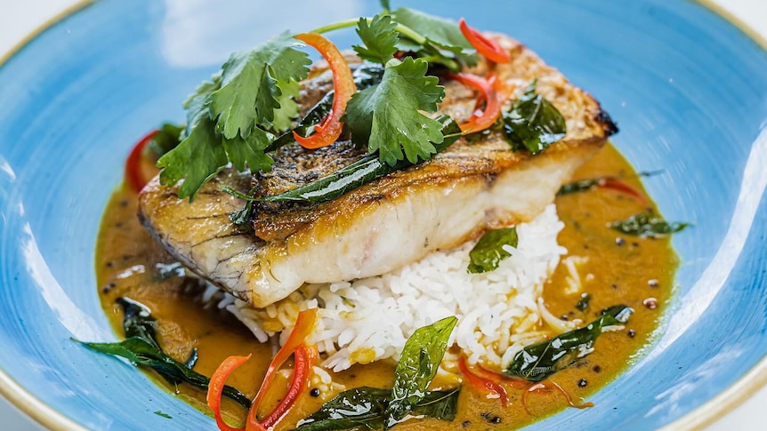 a cooked barramundi fillet on rice in a bowl.