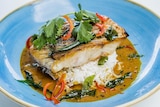 a cooked barramundi fillet on rice in a bowl.