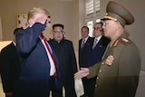 Donald Trump salutes a man in a green army uniform.